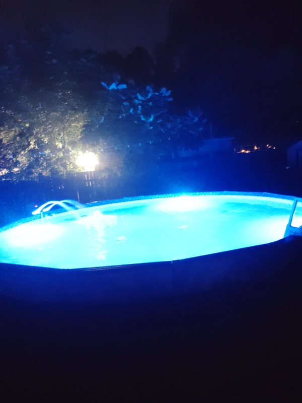 Above-ground pool glowing blue at night with a new liner