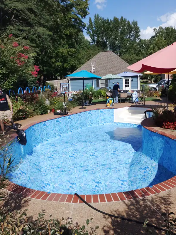 Freeform inground pool with a patterned liner and brick coping