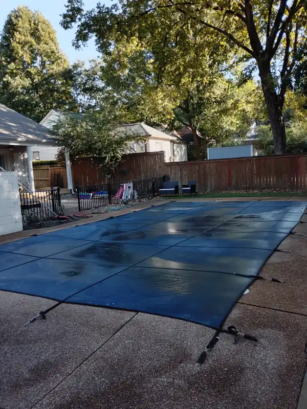 Inground pool under a mesh safety cover in autumn