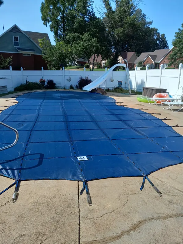 Blue mesh safety cover anchored over an inground pool